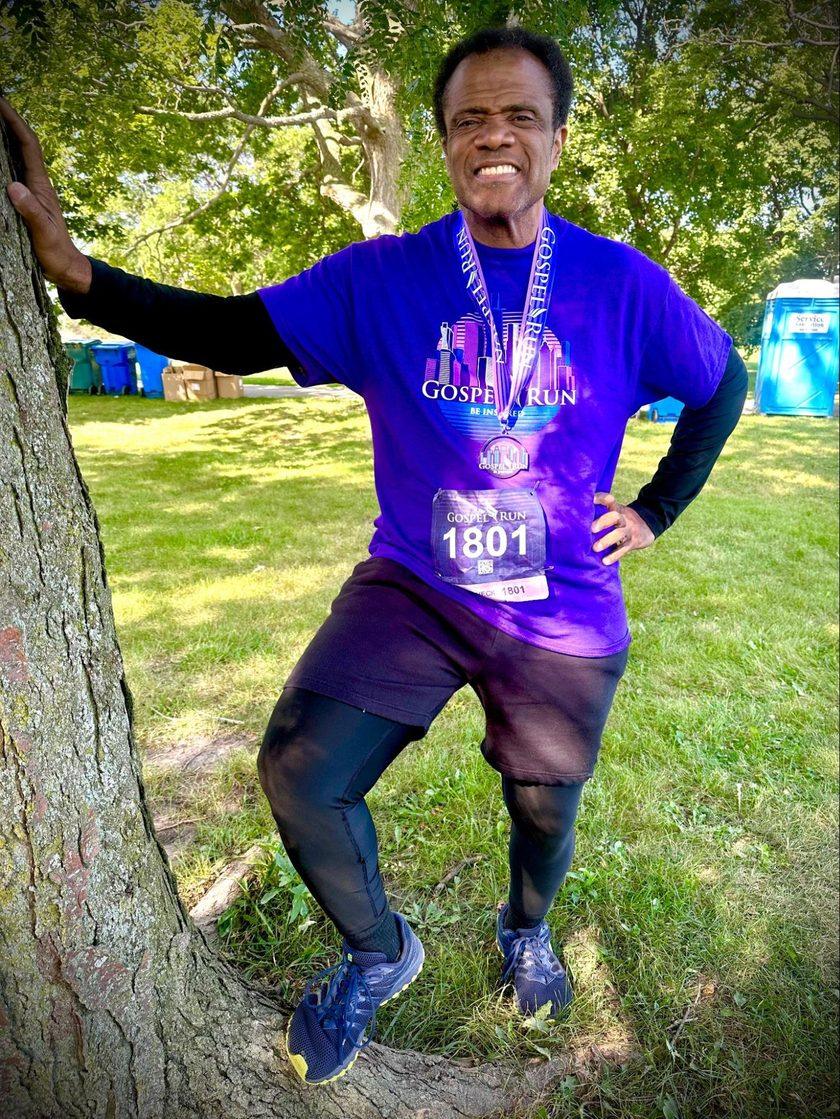 Dr. Kahan Sablo smiling at a Gospel Run race wearing his finisher medal and race bib