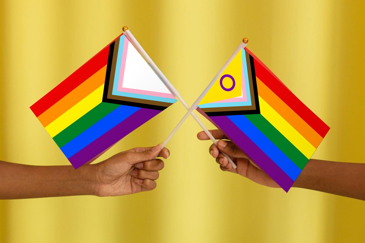 Two hands of different skin tones holding Progress Pride flags together, one with the intersex-inclusive gold triangle and purple circle