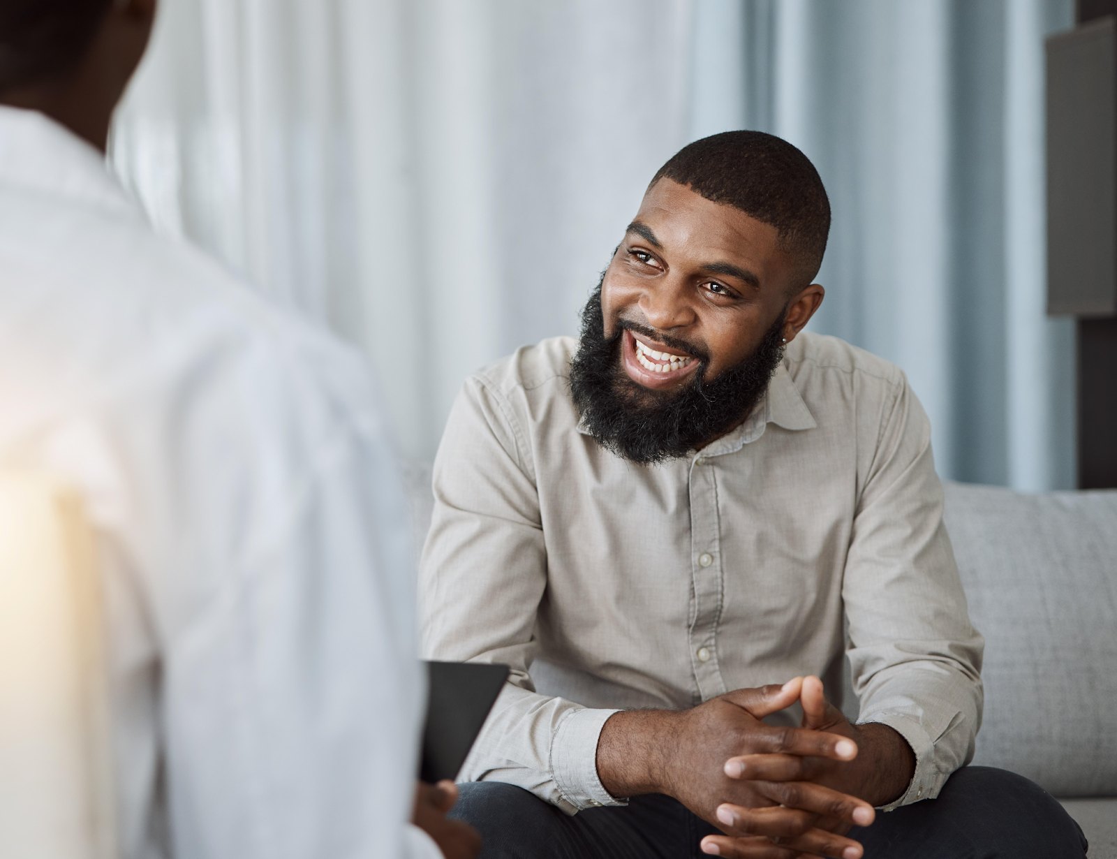 A Black man with a full beard smiling warmly during a counseling conversation