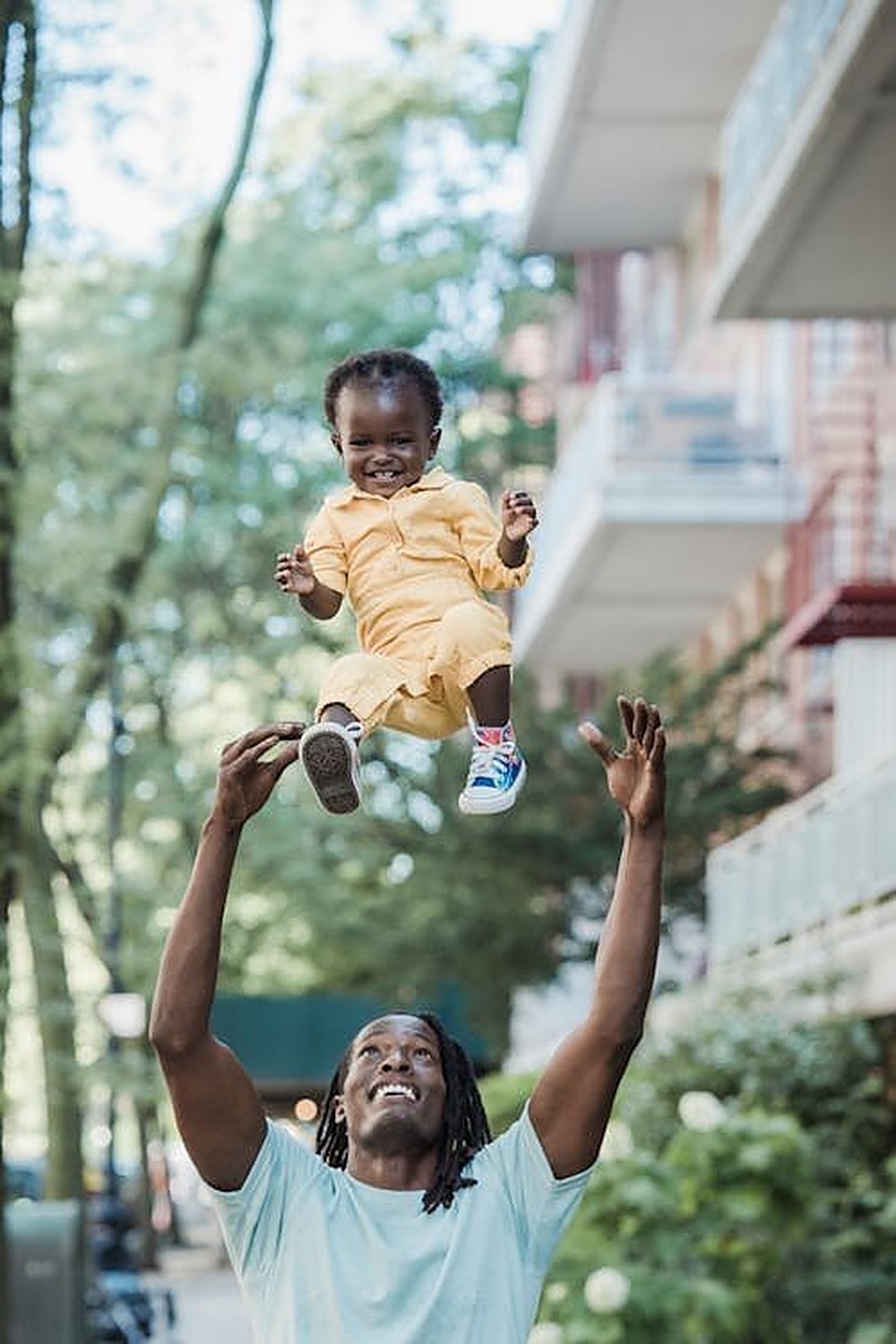 A father joyfully lifting his son into the air, celebrating community and family bonds