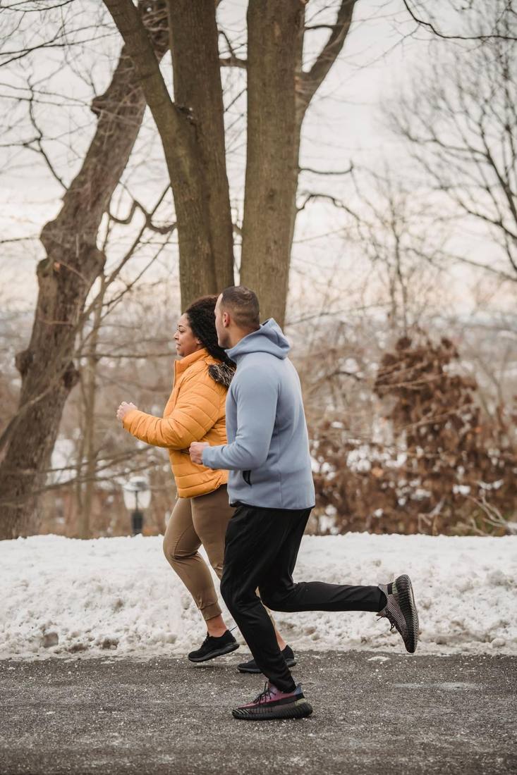 A diverse couple jogging together outdoors, supporting each other on a wellness journey
